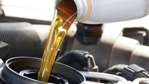 Slika predstavlja korak sipanja ulja motora u postupku Zamen ulje motora i filtera ulja. Iz sive kantice se u otvor za dolivanje ulja na motoru uliva žuto ulje motora.