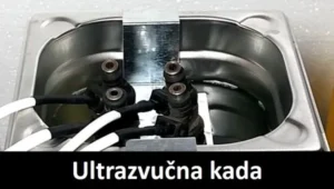 Ultrazvučna kada za čišćenje i pranje auto delova. Na slici se vidi postupak pranja brizgaljke koje su uronjene u tečnost ultrazvučne kade. U donjem delu slike na crnoj traci krupnim belim slovima piše Ultrazvučna kada